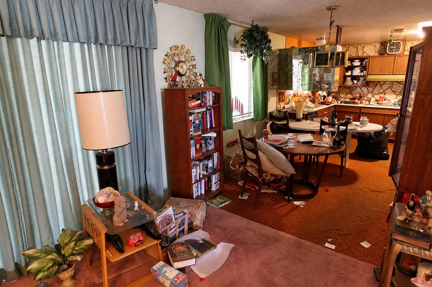 A lived-in family home with a bookcase, dining table and a kitchen still full of dishes and belongings